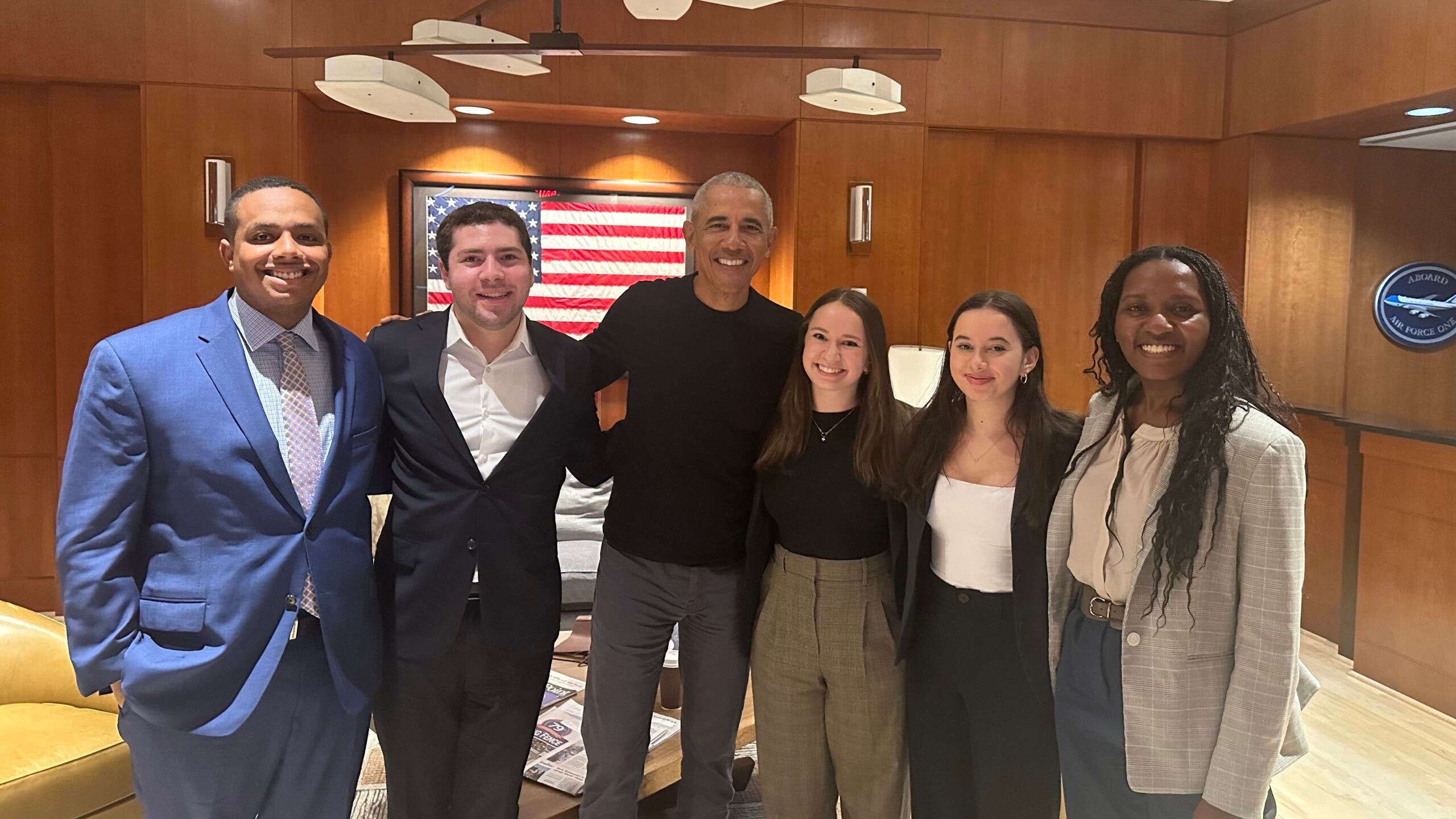 Group of six people posing for a photo in a professional setting, including former President Barack Obama