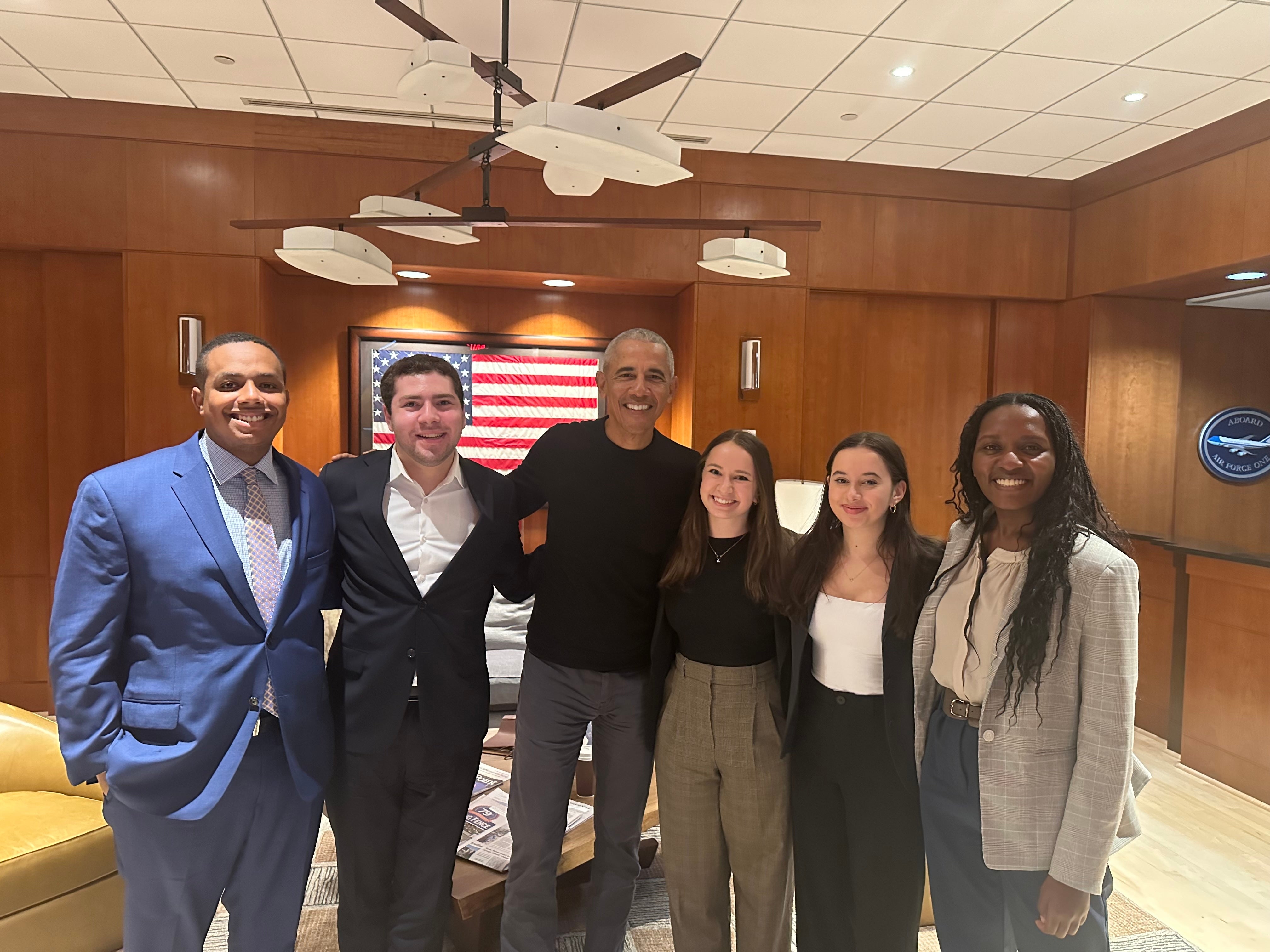 Group of six people posing for a photo in a professional setting, including former President Barack Obama