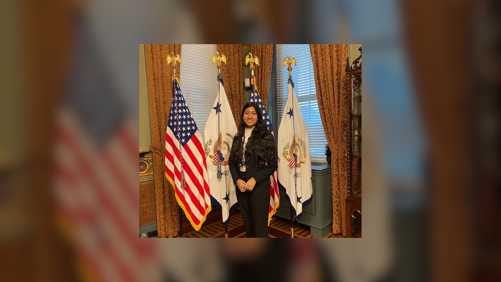 Esha Sharma stands in front of flags.