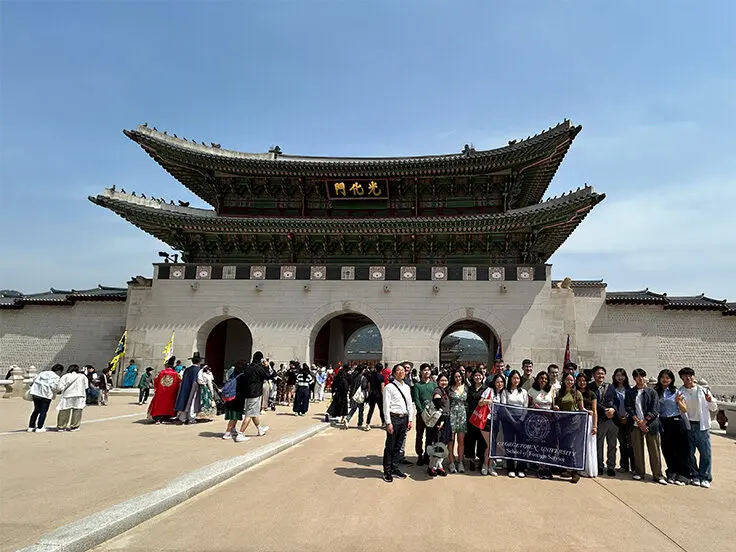 Students holding a Georgetown School of Foreign Service banner in front of the Kyŏngbok Palace in Seoul