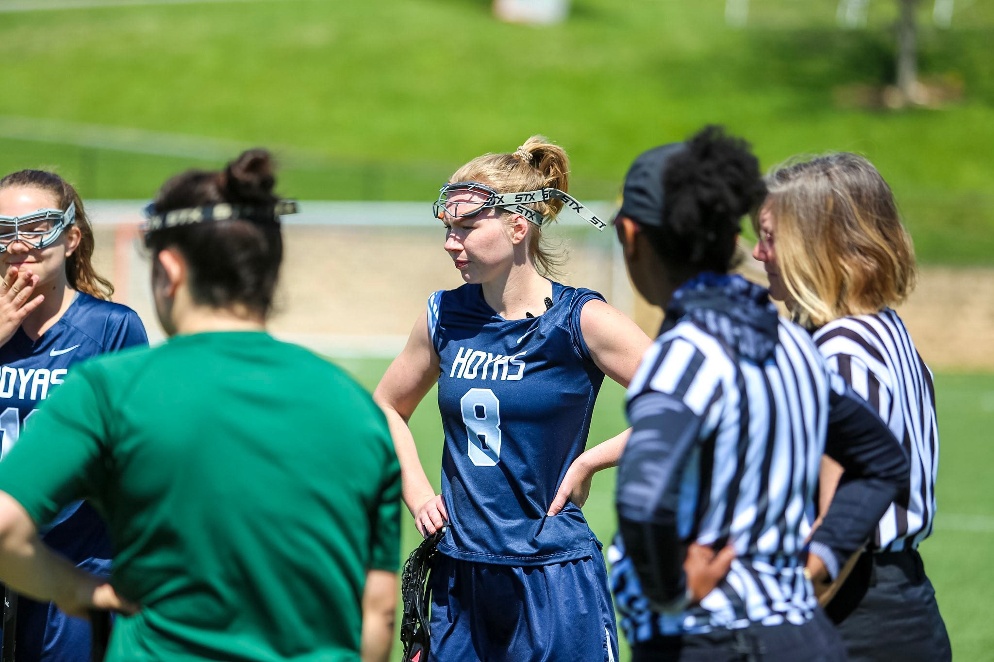 Paige Maylath, a blond woman in a sports uniform, stands among referees and other athletes on a field.
