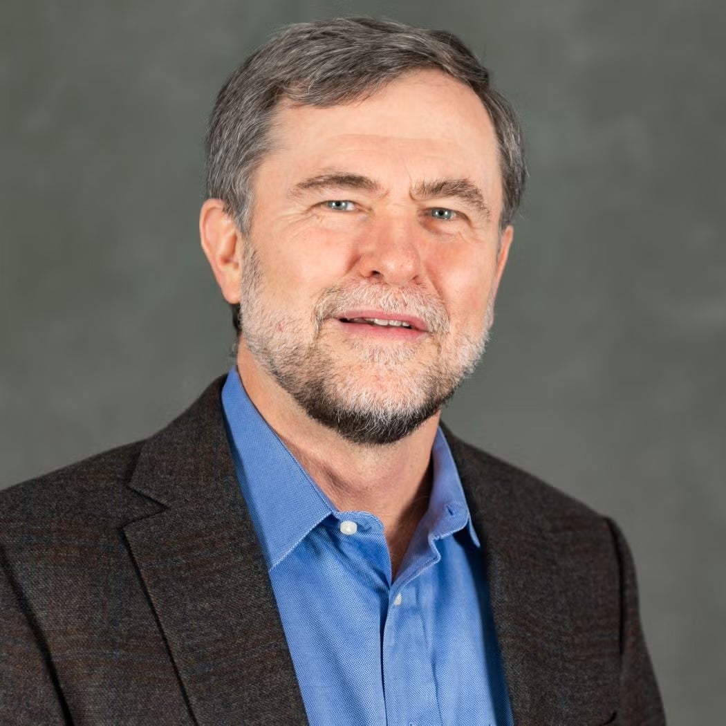 Steve Radelet wearing a blue button down shirt and dark gray jacket.