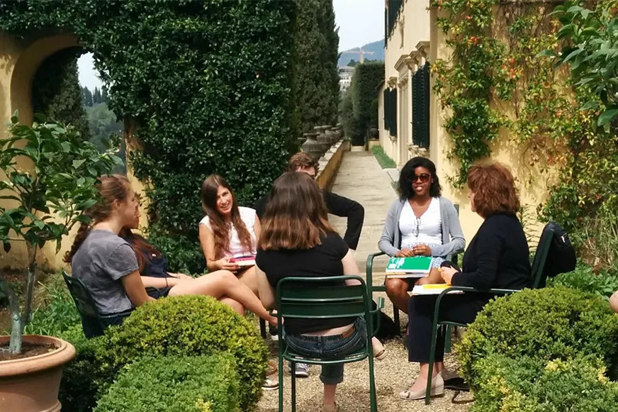 Group of students sitting in a circle in a garden in Europe.