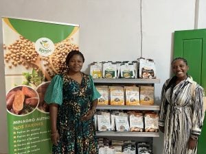 Two individuals standing beside a product display, smiling. The display features various packaged food products.