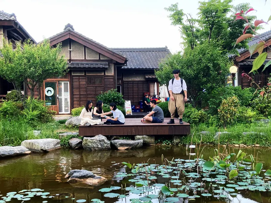 Students in japan sitting on a deck by a pond