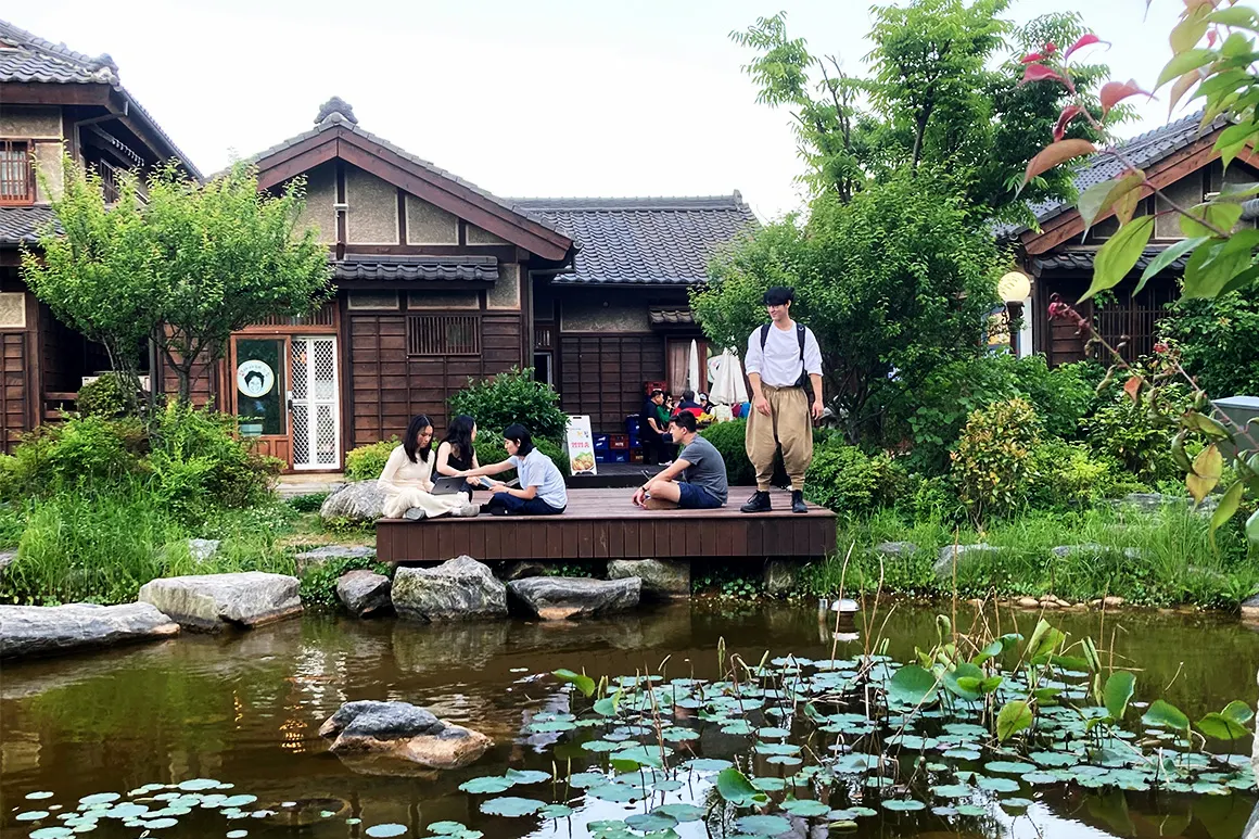Students in japan sitting on a deck by a pond