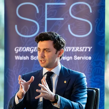 Senator Jon Ossof speaking, in front of a Georgetown University School of Foreign Service banner