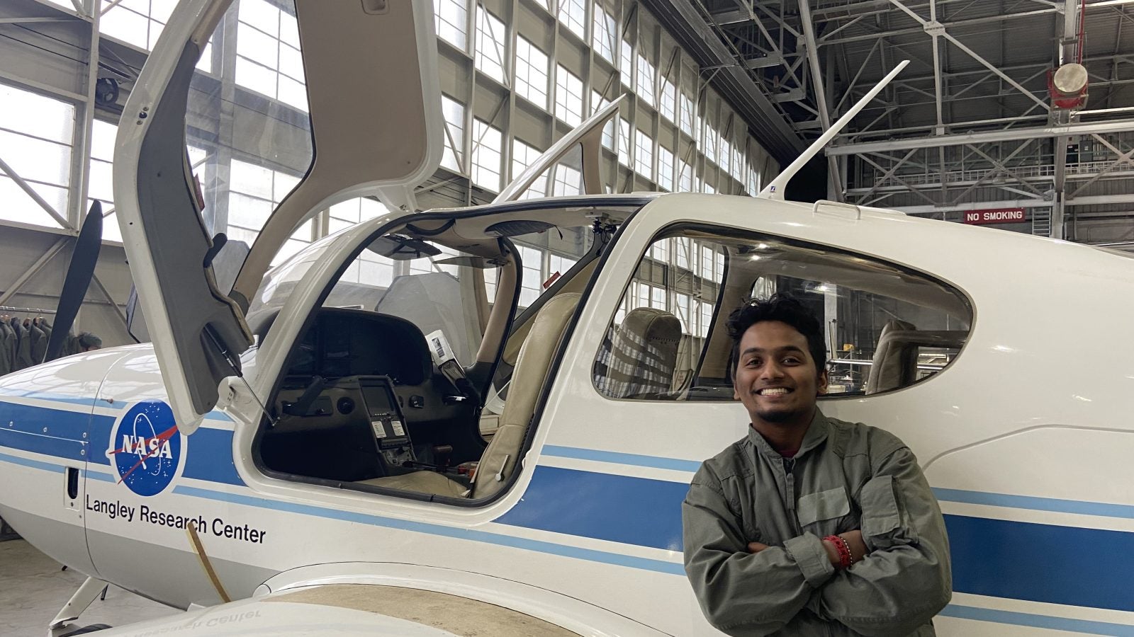 A person smiling next to a NASA Langley Research Center airplane inside a hangar.