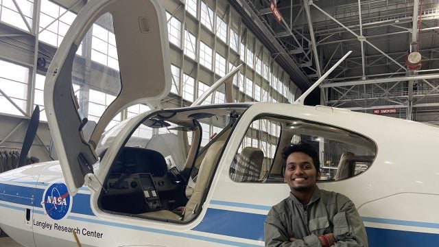 A person smiling next to a NASA Langley Research Center airplane inside a hangar.