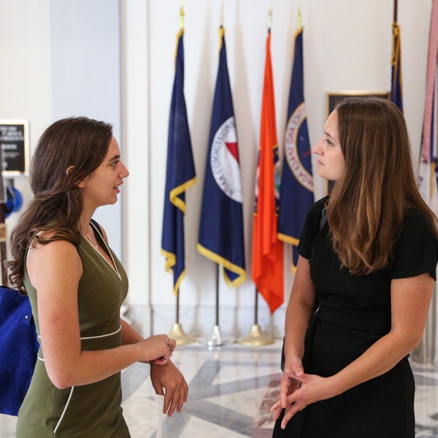 Students speaking to each other in front of a row of flags