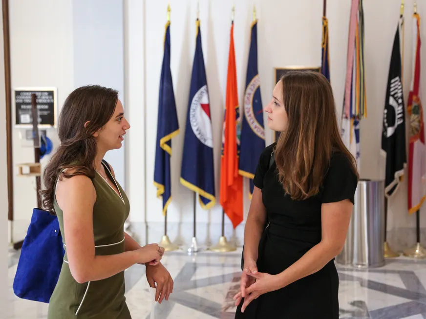 Students speaking to each other in front of a row of flags