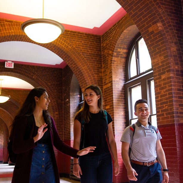 Students walking though a hallway, talking to each other