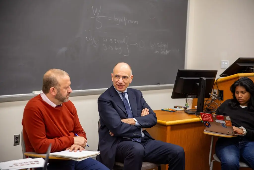 Enrico Letta sits in a chair at the front of a classroom with Professor Juan Manfredi.