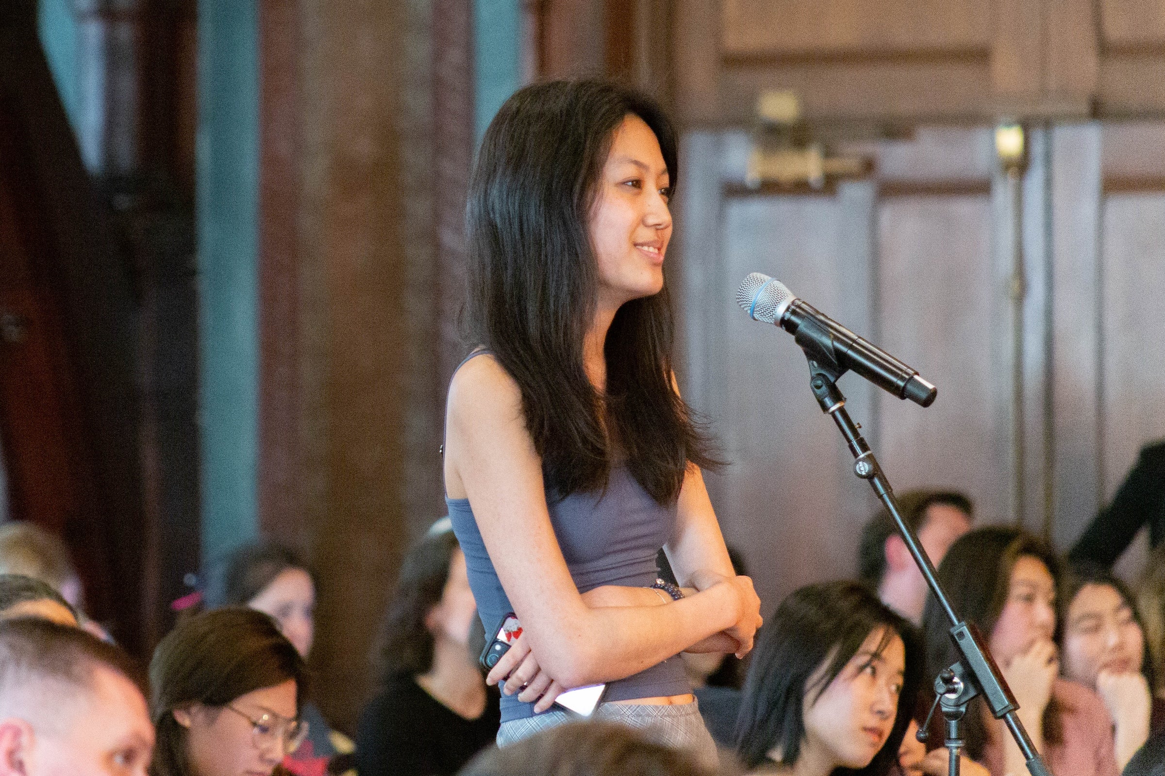 A woman stands at a standing microphon.