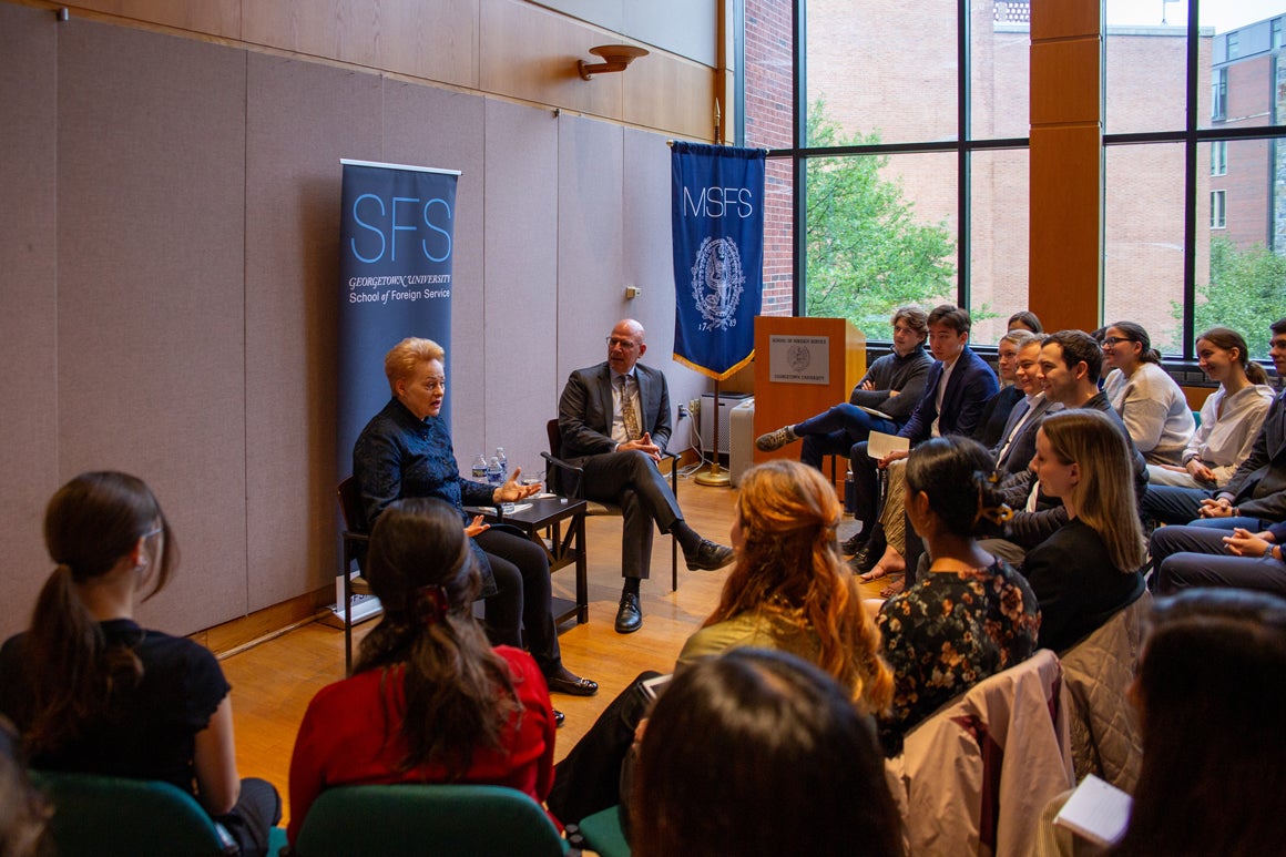 Dalia Grybauskaite and Dean Hellman sitting down in front of an audience of students engaged in conversation.
