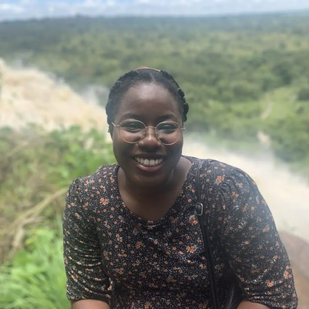 Aaliyah Ibrahim wearing a black floral blouse with glasses.