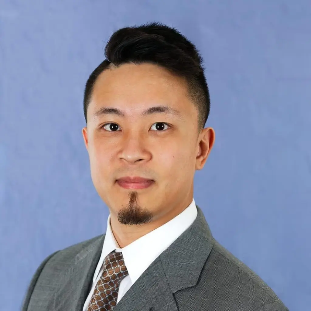 Andrew Yang wearing a gray suit, brown tie and white button-down shirt.