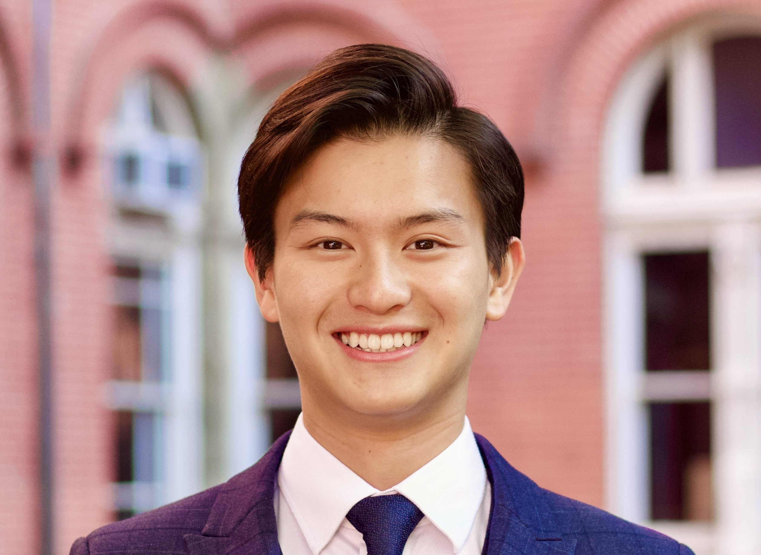 A young man with dark brown hair wearing a bright blue suit and tie.