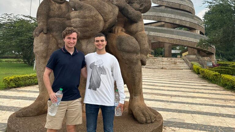 Ben Oestericher and another man stand in front of the Reunification Monument in Cameroon.