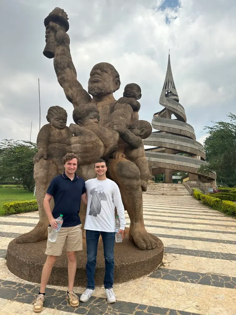 Ben Oestericher and another man stand in front of the Reunification Monument in Cameroon.