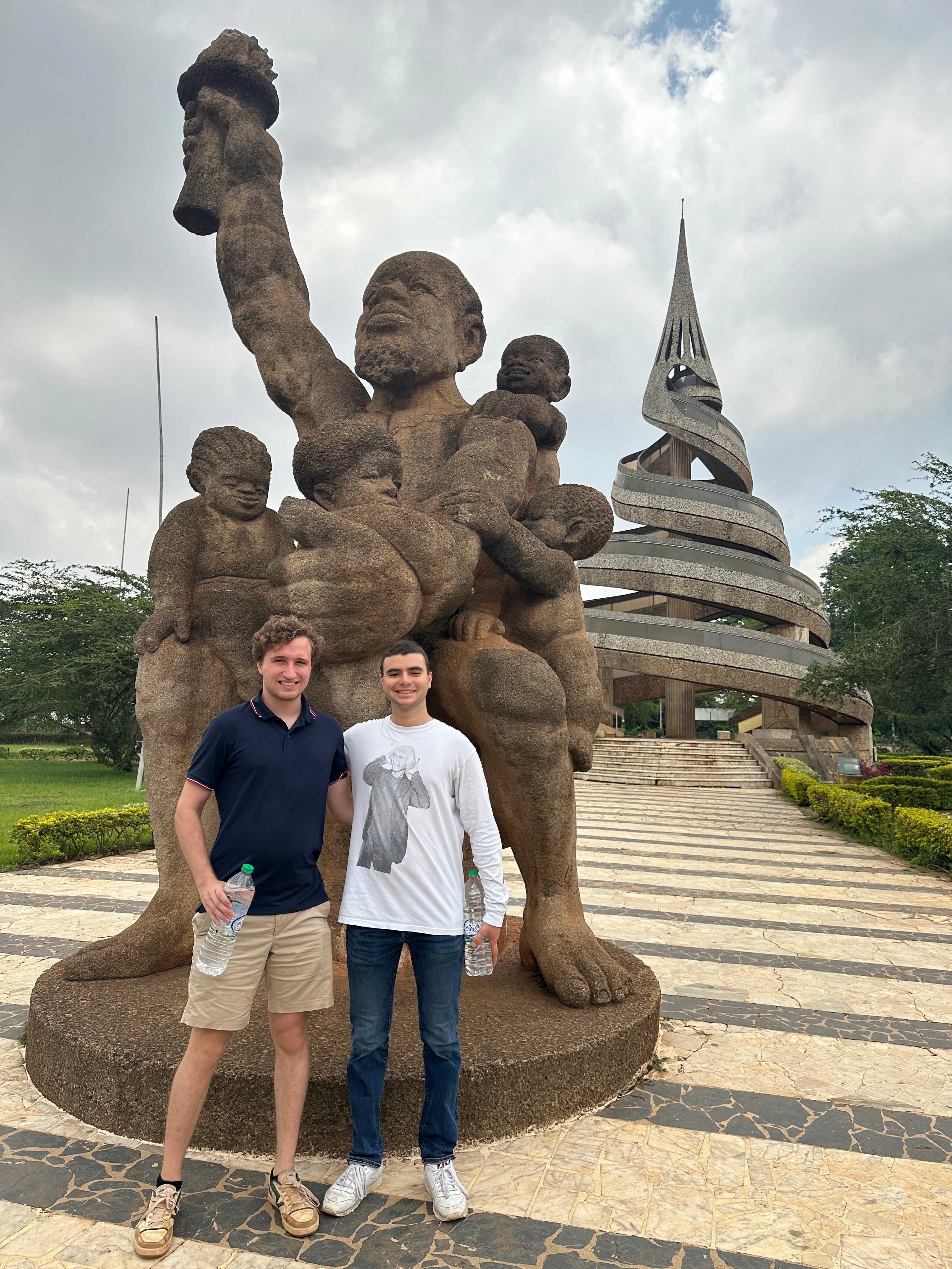 Ben Oestericher and another man stand in front of the Reunification Monument in Cameroon.