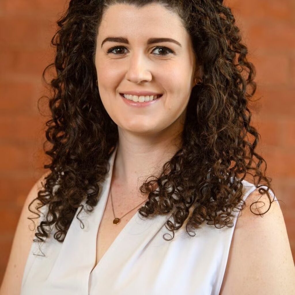 Claire Sullivan wearing a white sleeveless blouse.