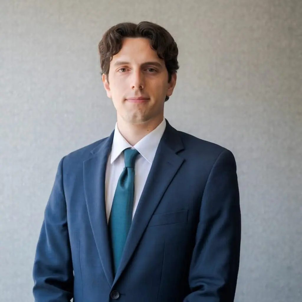 Daniel Bonomo wearing a navy blue suit, turquoise tie, and a white button down shirt.