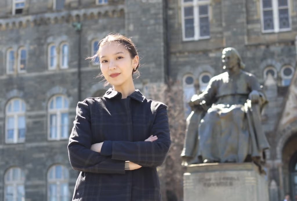 Darina Zhunussova wearing a dark jacket standing in front of Healy Hall.