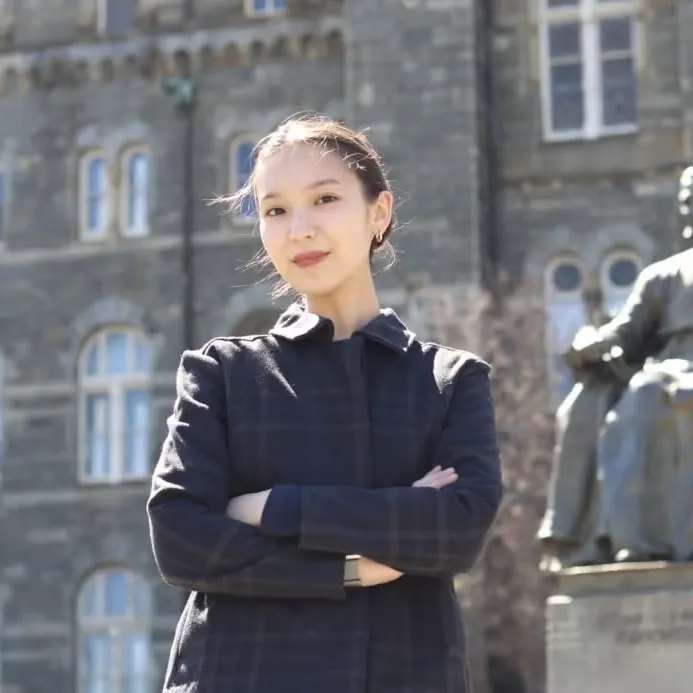 Darina Zhunussova wearing a dark jacket standing in front of Healy Hall.