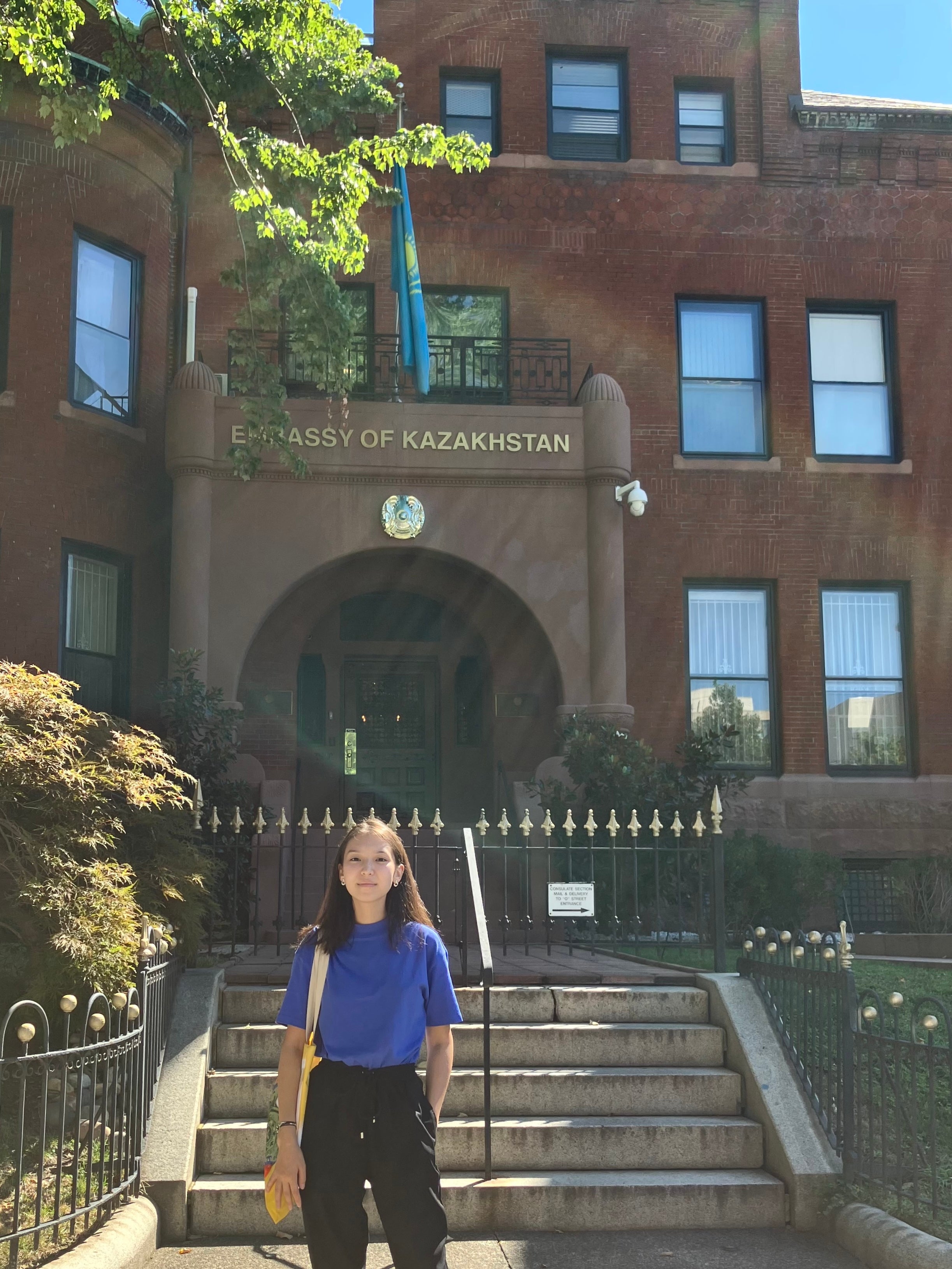 Darina Zhunussova stands in front of the Embassy of Kazakhstan front steps.