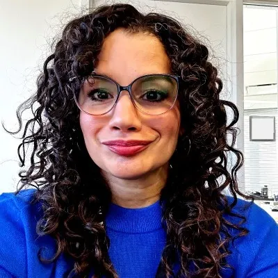 Denisse Bonilla Chaoui wearing a bright blue blouse and glasses.