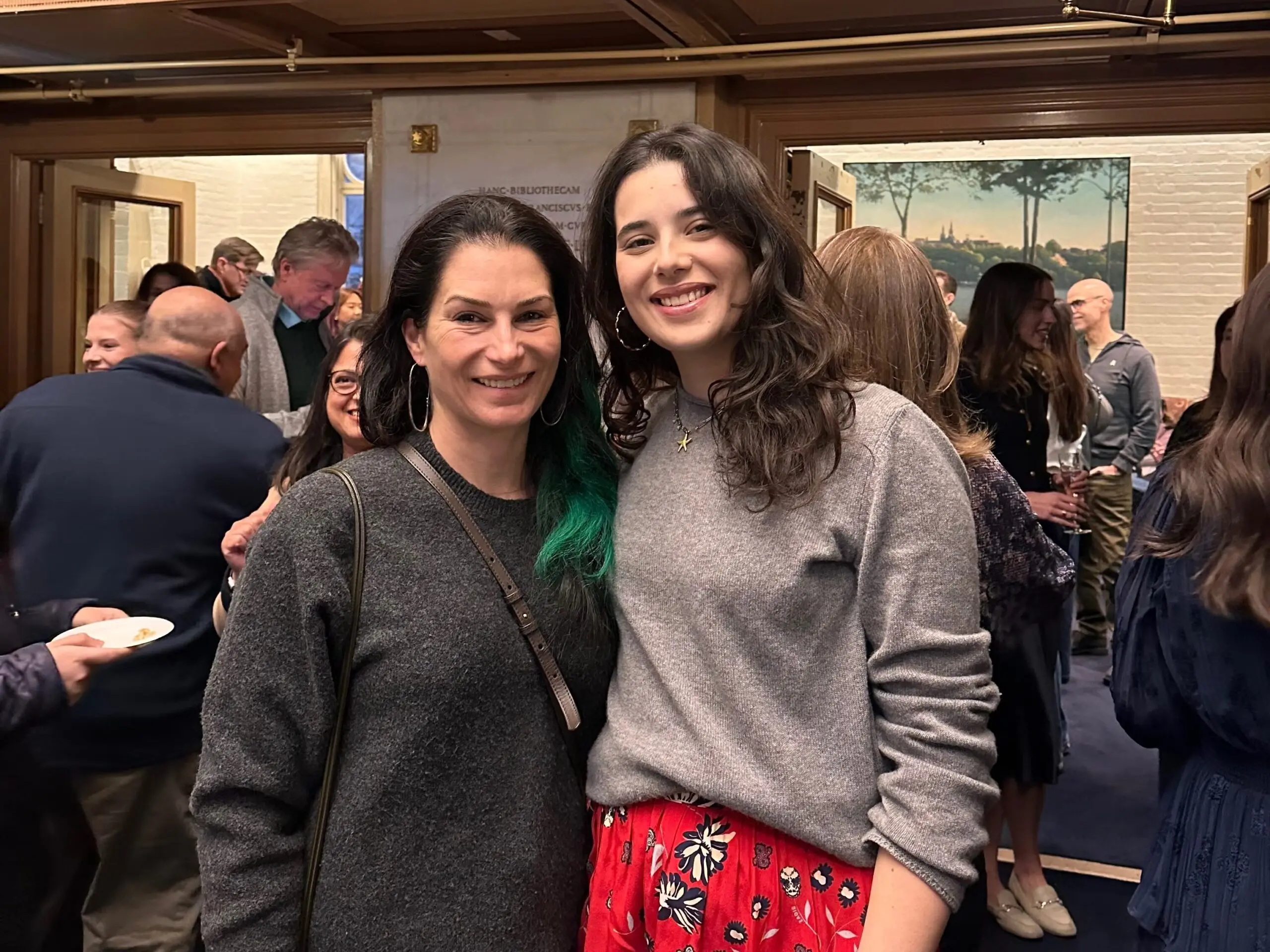Two women posing for a photo in a room with elegant décor in the background.