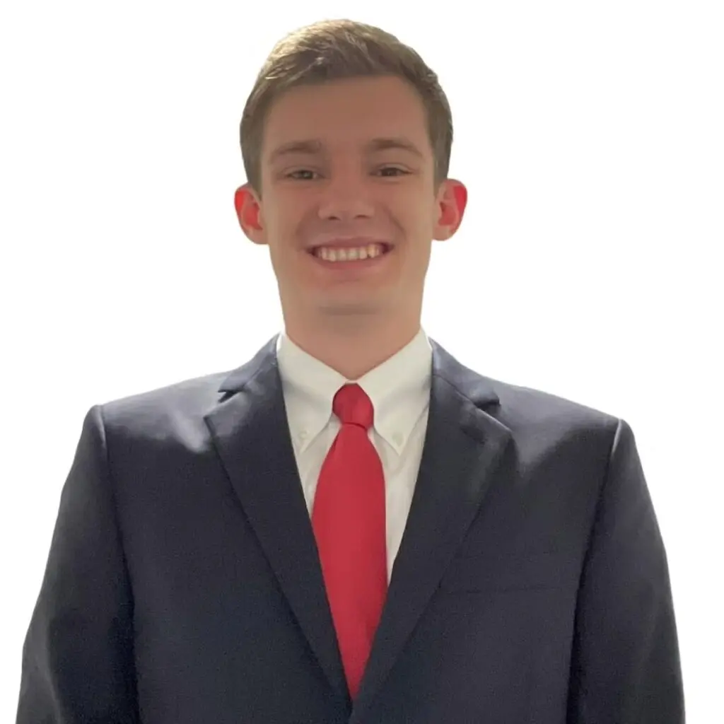 Evan McDonnell wearing a dark blazer and white button-down shirt with a red tie.