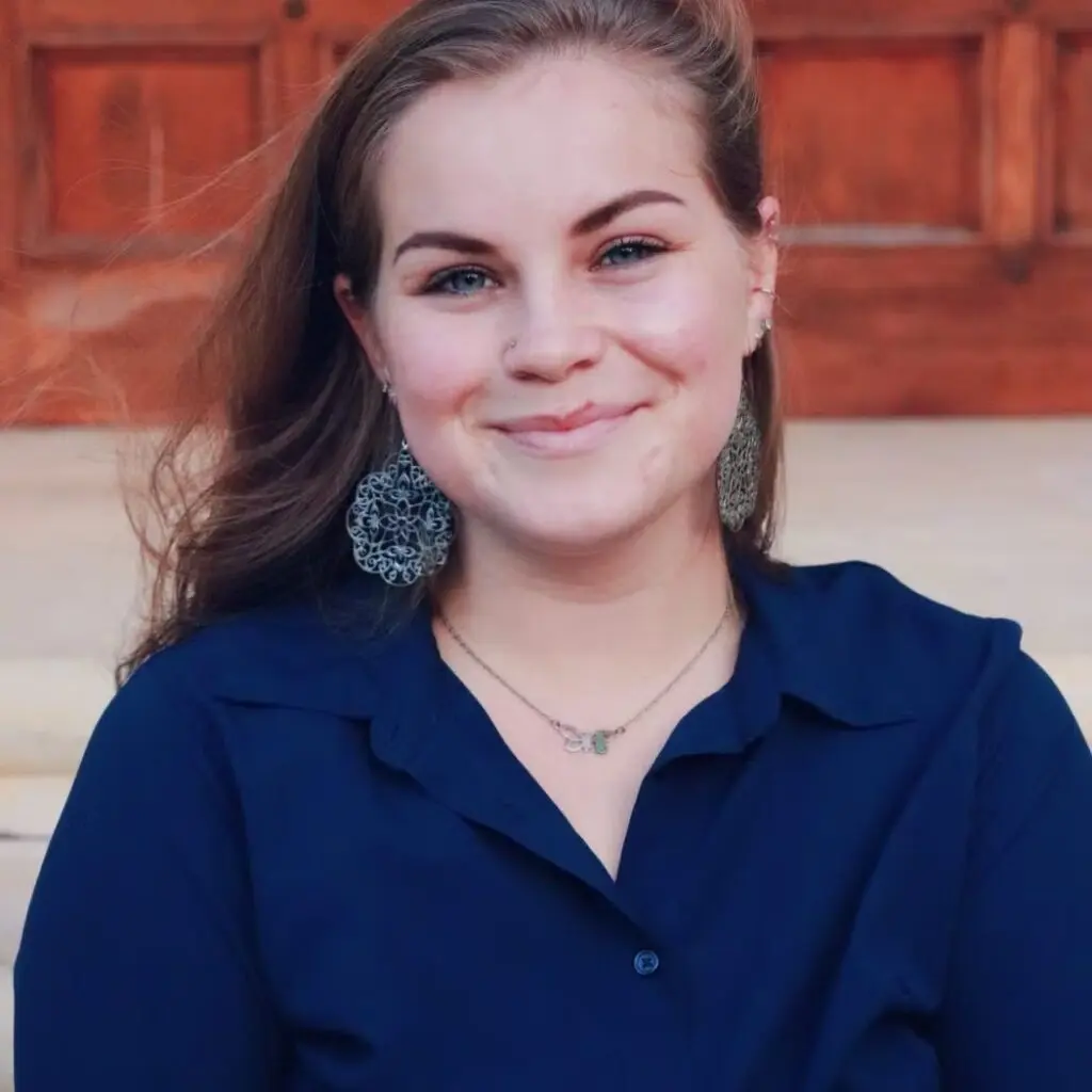 Frances Turk wearing a blue button-down shirt and earrings.