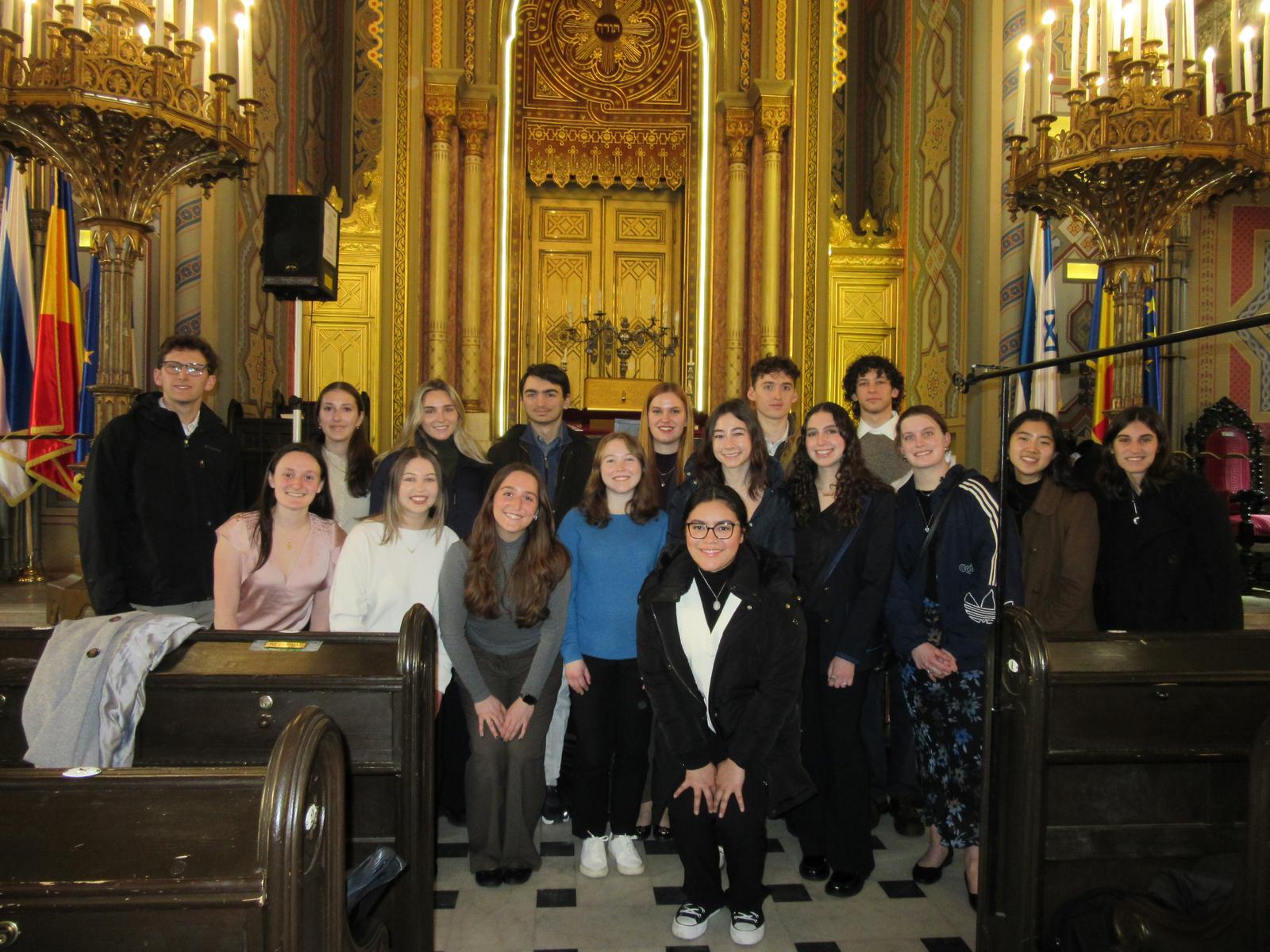 Group of students posing for a photo in an ornate room with elaborate golden decorations.