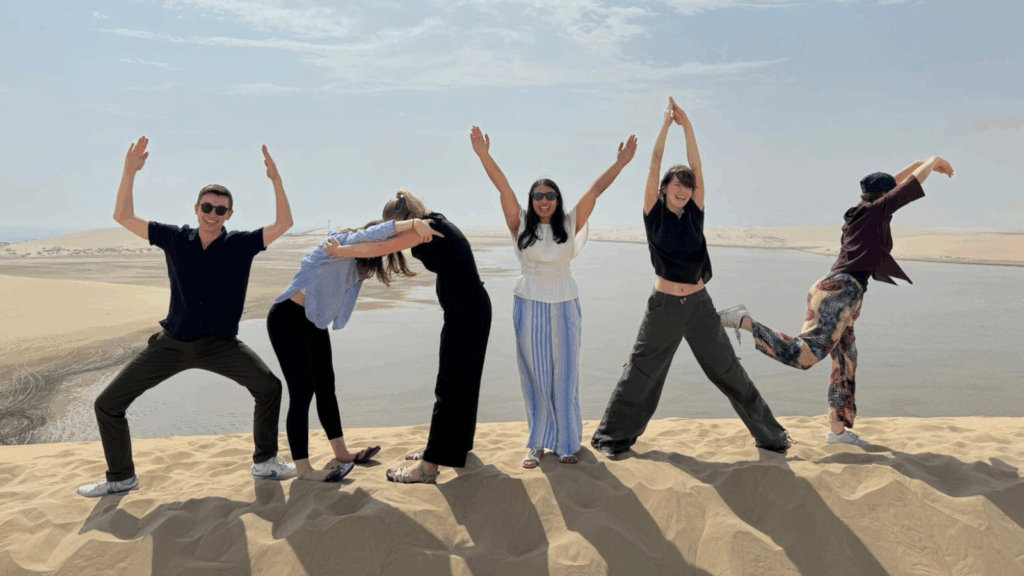 A group of six students spelling "HOYAS" with their bodies in the desert in Qatar.
