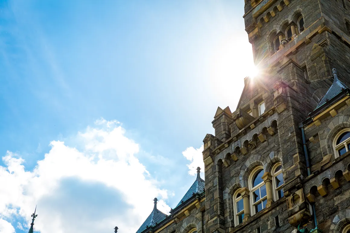 Healy Hall building with a bright blue sky and sun flare