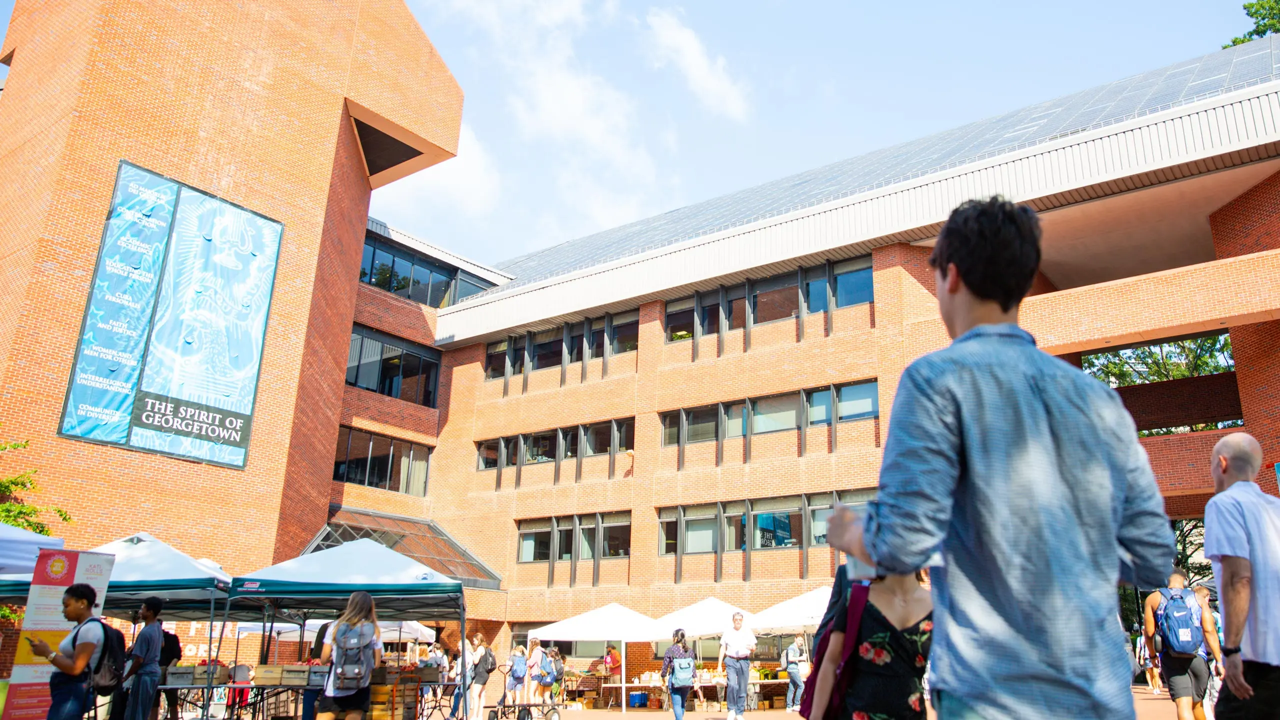 Intercultural center building in a sunny day. Students walking outside of it, tents selling food.