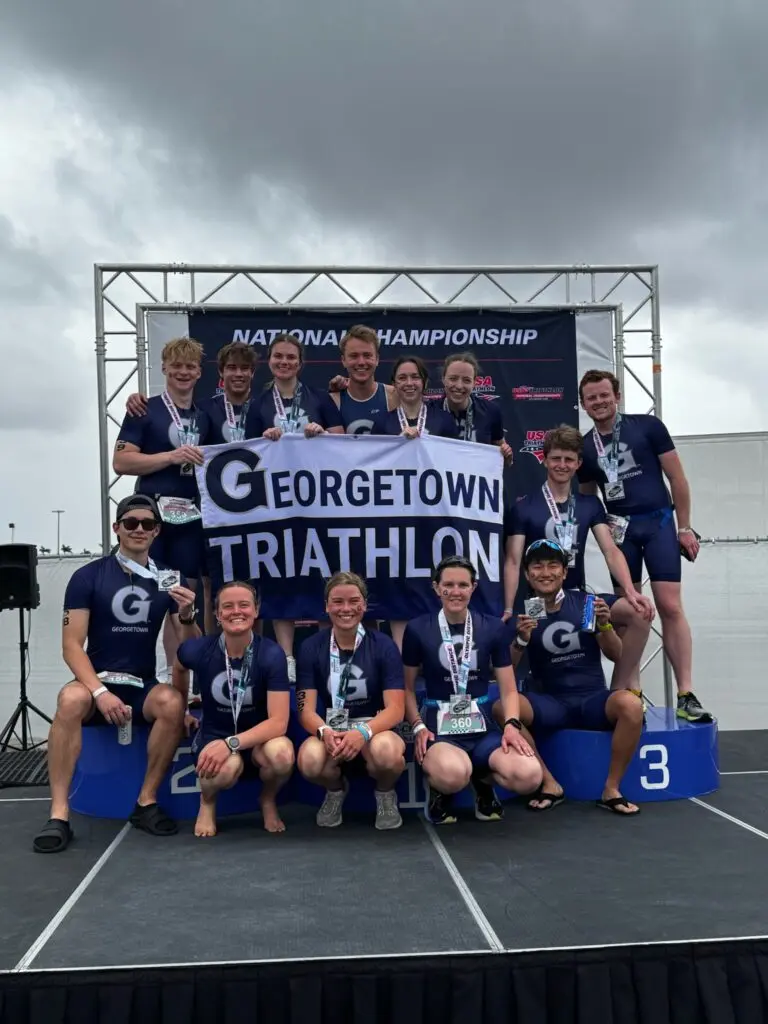 Marina McPhail poses with her Georgetown Triathlon team holding a banner.