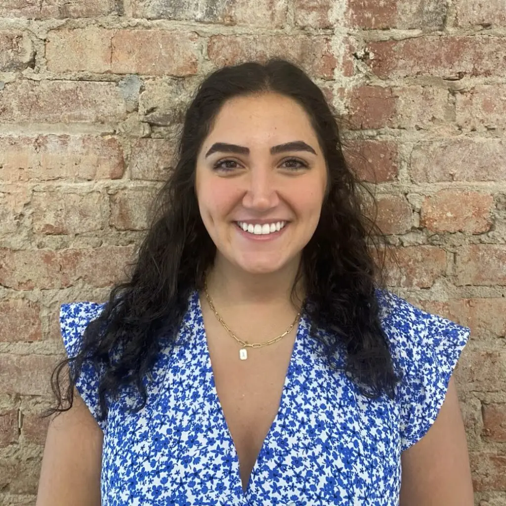 Isabelle Mansour wearing a blue and white floral shirt against a brick background.