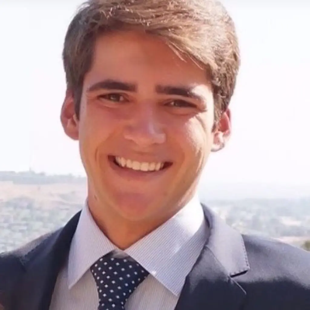 James Brady wearing a dark blazer and light gray button-down shirt with a navy blue polkadot tie.