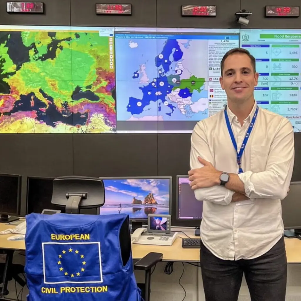 Javier Ochoa standing in front of screens displaying maps of Europe.