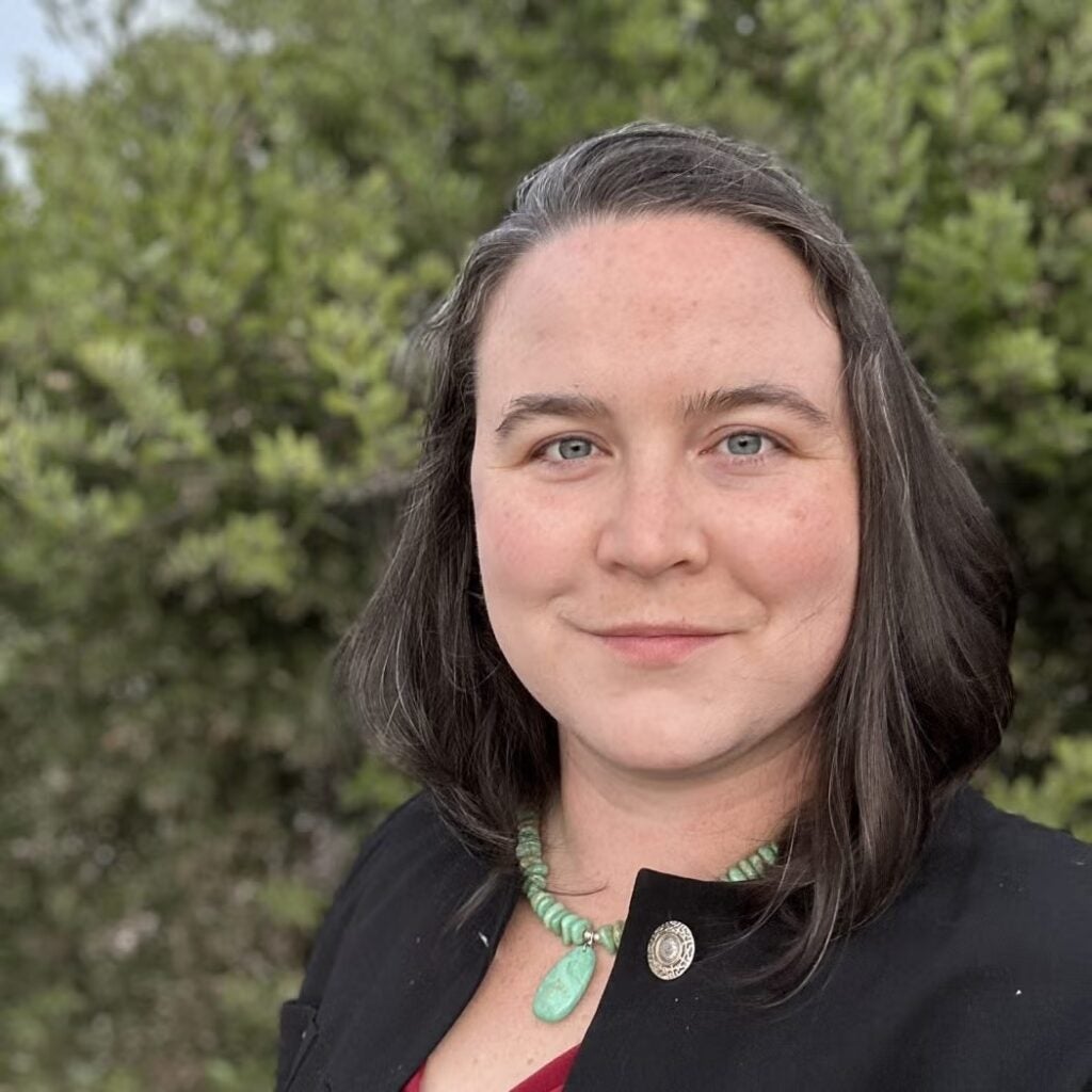 Jessica Dickinson Goodman wearing a black jacket and green stone necklace.
