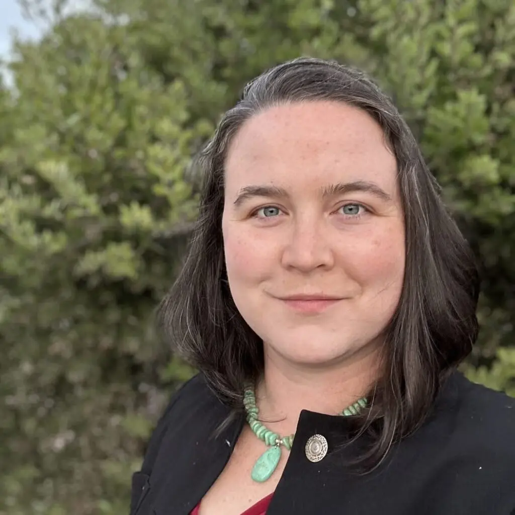 Jessica Dickinson Goodman wearing a black jacket and green stone necklace.