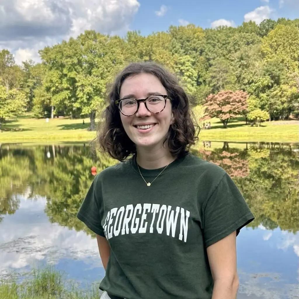 Johanna Lichtschlag in front of a lake, wearing a green Georgetown shirt and glasses,