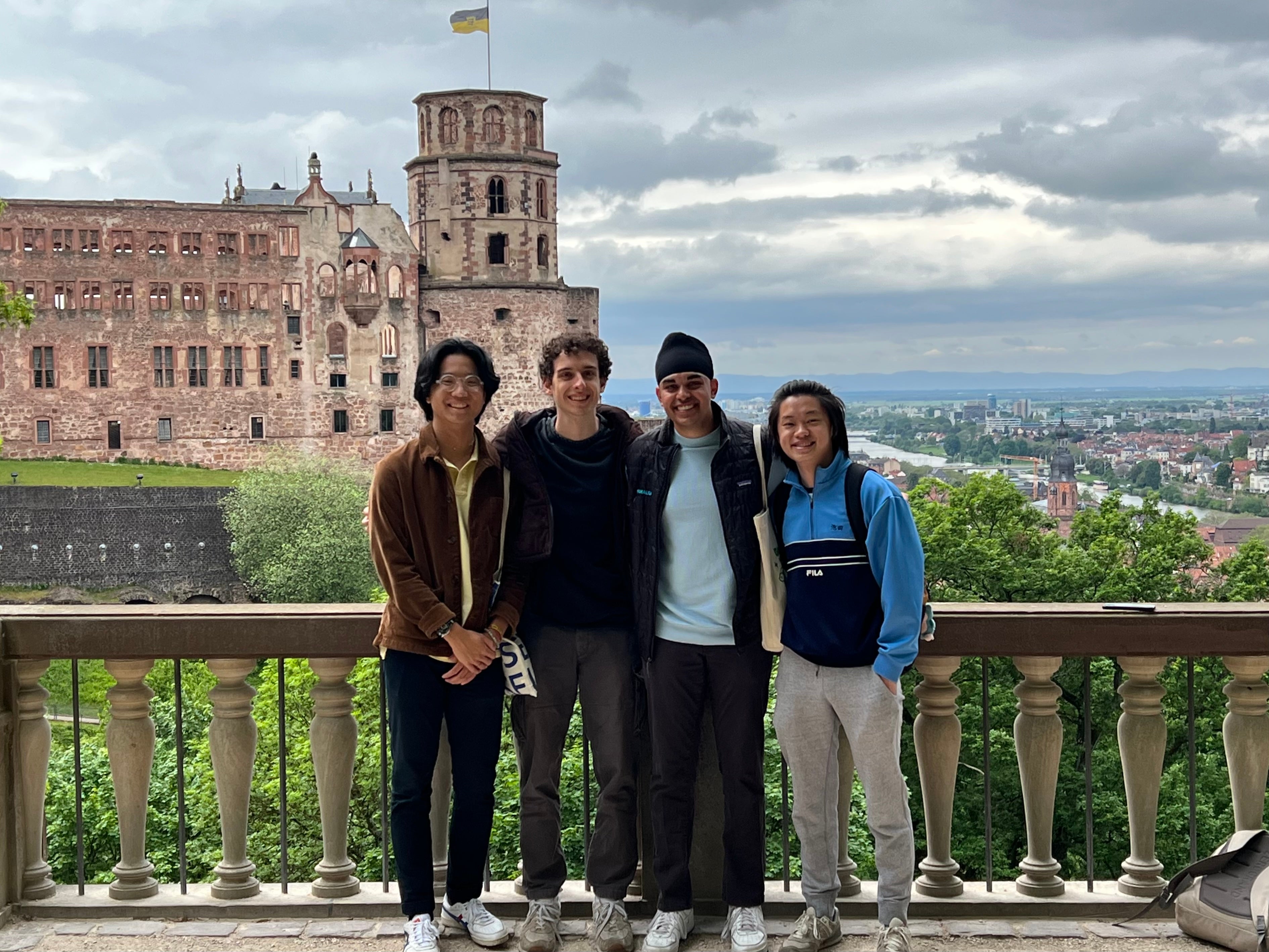 Jonathan Lee stands with three friends on a balcony in front of a castle in Europe.