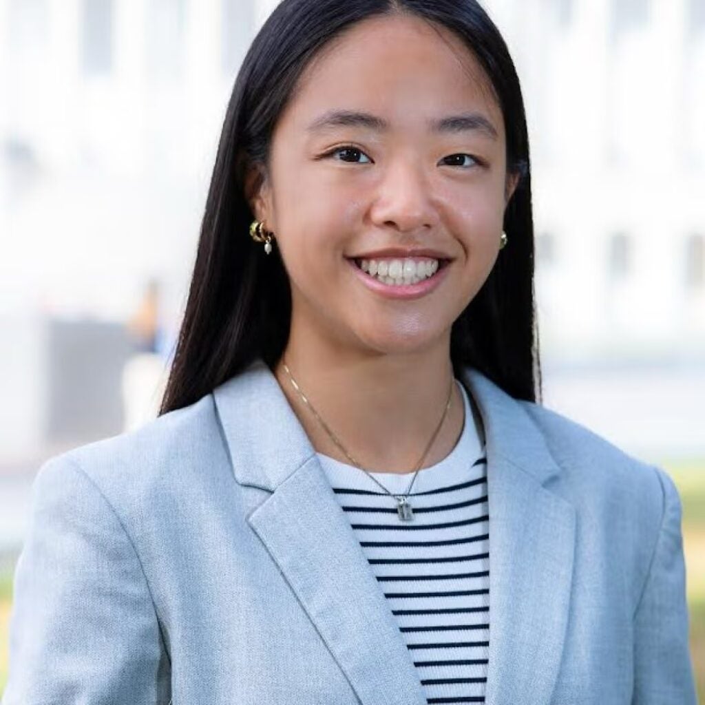 Katie Cheung wearing a black and white striped shirt and light blue blazer.