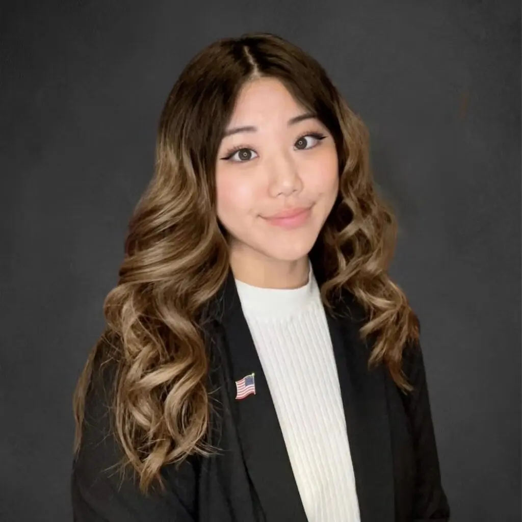 Kaylin Kim wearing a white sweater with a black blouse and an American flag pin.