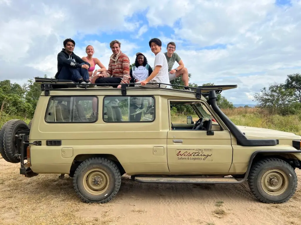 Keith Richards and five friends sit on top of a jeep that has "Wild Things Safaris & Logistics" written on it.