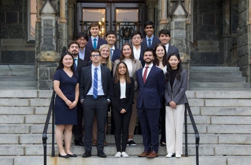 Keith Richards stands witha. group of students all wearing suits on the steps of Healy Hall.